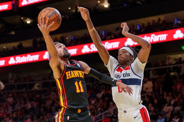 Atlanta Hawks guard Trae Young (11) goes up for a layup while guarded by Washington Wizards guard Bilal Coulibaly, right, during the first half of an Emirates NBA Cup basketball game, Friday, Nov. 15, 2024, in Atlanta. (AP Photo/Jason Allen)