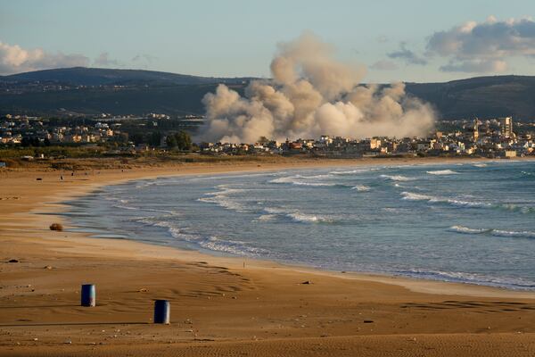 Smoke rises between buildings hit in Israeli airstrikes near the Palestinian refugee camp of Rashidiyeh, as seen from Tyre city, south Lebanon, Tuesday, Nov. 26, 2024. (AP Photo/Hussein Malla)