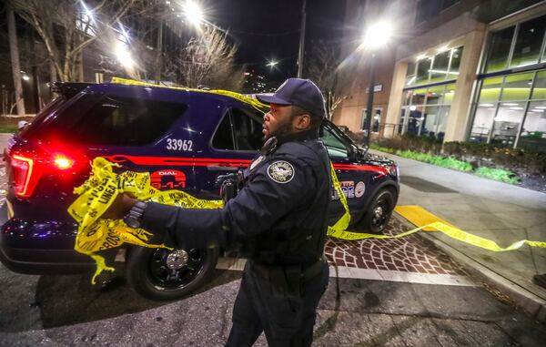 An Atlanta police officer gathers crime scene tape after the double shooting Friday.