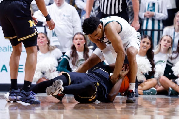 Michigan State guard Jaden Akins, top, and Michigan guard L.J. Cason, bottom, wrestle for the ball during the first half of an NCAA college basketball game, Sunday, March 9, 2025, in East Lansing, Mich. (AP Photo/Al Goldis)