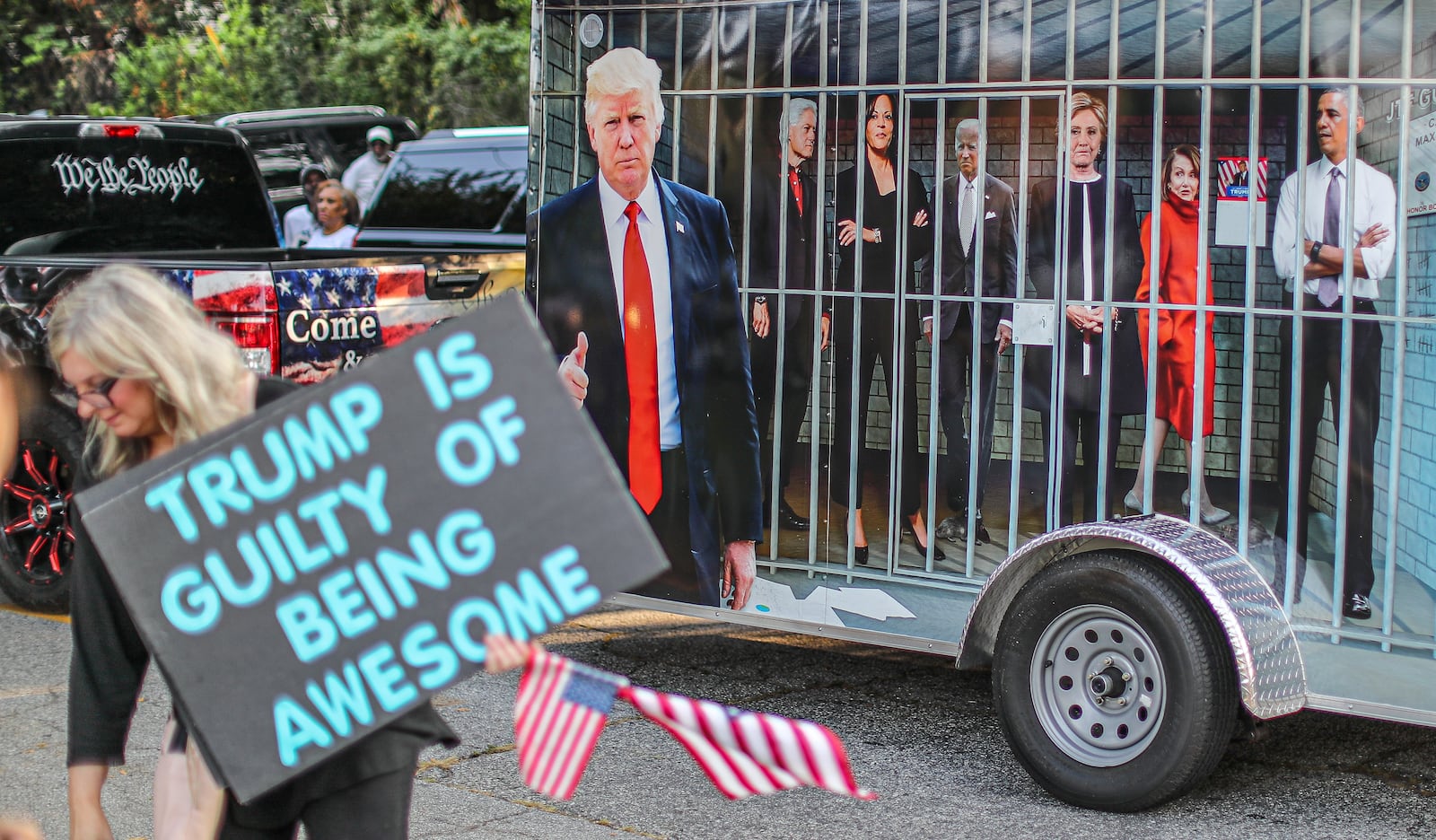 August 24, 2023 Atlanta:  Jennifer Vliet (left) brought her message along Rice Street as a wrapped vehicle drove by showing famous democrats in jail late Thursday morning, Aug. 24, 2023 where there were more than 100 protestors gathered outside the jail, and they were prepared to wait for hours until the anticipated arrival of former President Donald Trump. (John Spink / John.Spink@ajc.com)


