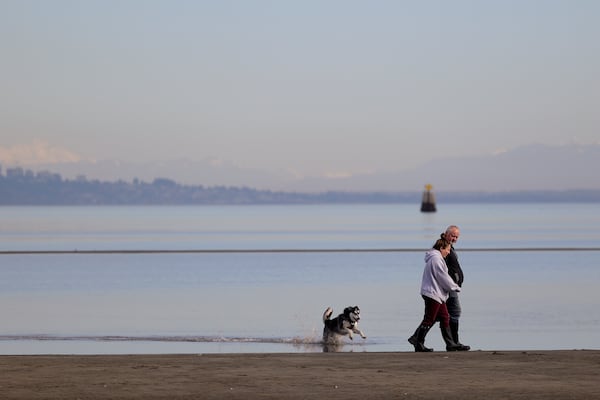 People walk along Maple Beach ahead of a buoy demarcating the United States-Canada border, Saturday, March 1, 2025, in Point Roberts, Wash. (AP Photo/Ryan Sun)