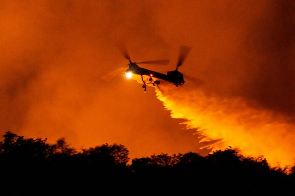 A helicopter drops water on the Palisades Fire in Mandeville Canyon, Saturday, Jan. 11, 2025, in Los Angeles.(AP Photo/Etienne Laurent)