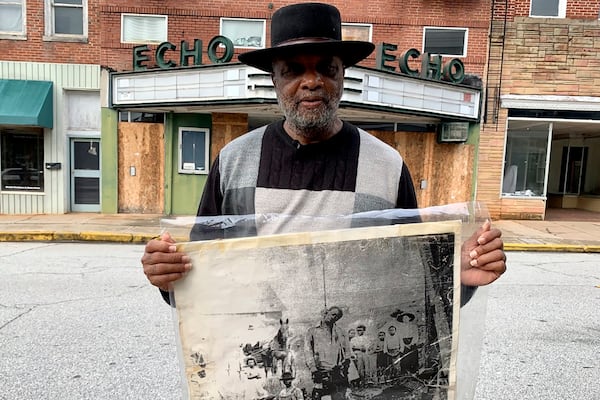 In this Monday, Jan. 13, 2020 photo, Rev. David Kennedy stands outside the Echo Theater holding a photo of his great uncle's lynching, in Laurens, S.C. Kennedy has fought for civil rights in South Carolina for decades. (AP Photo/Sarah Blake Morgan)