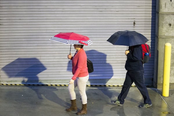 Pedestrians use their umbrellas to shield themselves from a light shower while walking down 6th Street.  ALYSSA POINTER / ALYSSA.POINTER@AJC.COM