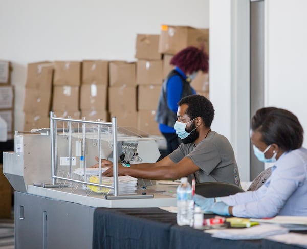 On the suite level at State Farm Arena, Fulton County election officials work to count absentee ballots on Monday, November 2, 2020.  The process includes machines that cut open the envelopes, people who sort the paperwork, scanning stations where the data is collected and boxing of the recorded ballots for transport to English Avenue where Fulton County's official count is assessed.  The physical ballots and the scanned date will be transported on Tuesday after all absentee ballots are counted.  (Jenni Girtman for The Atlanta Journal-Constitution)