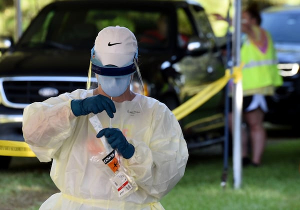 Cathy Webb, LPN, secures a COVID-19 test outside Glynn County Health Department in Brunswick on July 14. Georgia’s testing plan omits any mention of lab turnaround times, a problem that, in part, is keeping the state from achieving its testing goal. (Ryon Horne/RHORNE@AJC.COM)