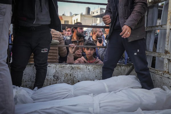 A boy looks at the bodies of Palestinians killed in the Israeli bombardment of the Gaza Strip as they are brought for burial at Al-Aqsa Hospital in Deir al-Balah, Wednesday, Jan. 15, 2025. (AP Photo/Abdel Kareem Hana)