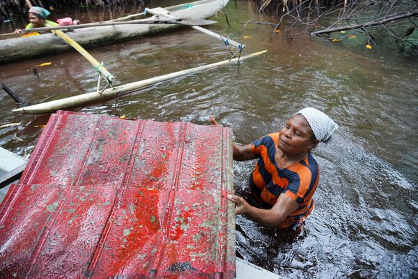 Paula Hamadi cleans up trash as she collects clams in a mangrove forest where only women are permitted to enter in Jayapura, Papua province, Indonesia on Wednesday, Oct. 2, 2024. (AP Photo/Firdia Lisnawati)