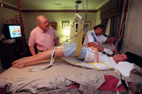 In this November 2000 photo, David Jayne is attended by his father, Bill, and a caregiver, Rose Delisser. The sling and hoist above his bed were used to elevate him so his lungs could be drained of fluid. 