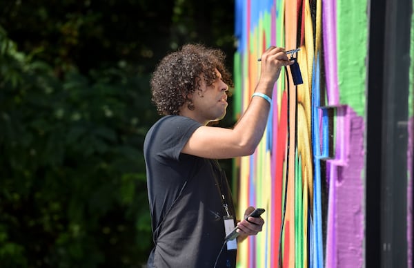 Roberto Hernández works on a mural outside Atlanta Package store on Buford Hwy on Friday, September 15, 2017. Roberto Hernández is a painter working on a mural as part of the Living Walls project along Buford Highway. He is also a DACA recipient. HYOSUB SHIN / HSHIN@AJC.COM