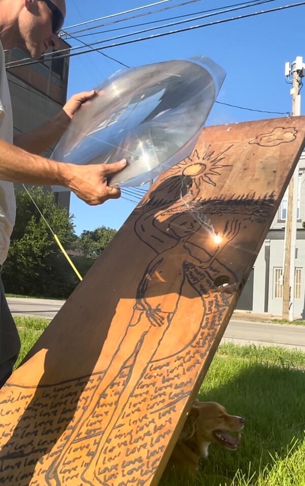 Artist Billy Keith of Louisville, Kentucky, creates his work with a giant magnifying lens that harnesses the sun to burn designs into wood. Keith is showing his art for the first time at Finster Fest this year. Photo: Courtesy of Michele Keith