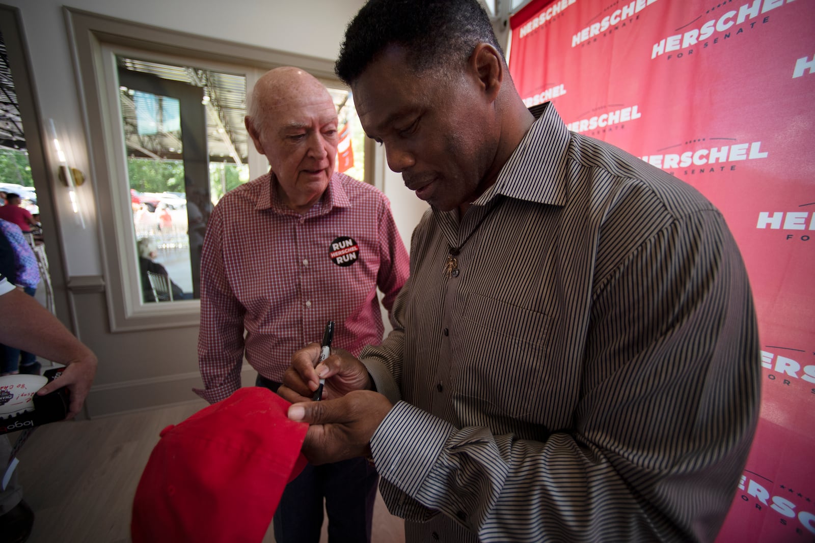 Republican Senate canididate Herschel Walker, signs an autograph after Walker spoke to supporters during a campaign stop, Saturday, May 14, 2022, in Ellijay, Ga. (AP Photo/Mike Stewart, Pool)