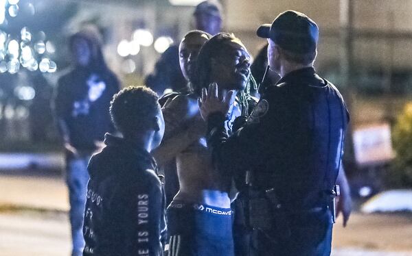 A bereaved relative is calmed by Atlanta police officers outside a fire station on Fairburn Road, where a shooting victim was pronounced dead inside a vehicle.