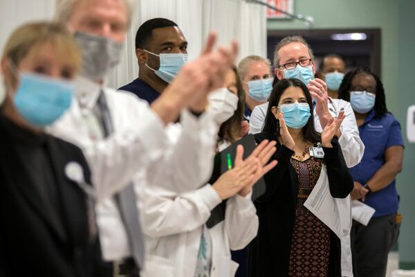 Healthcare professionals at St. Joseph's Candler hospital, including Dr. Ana M. Concepcion, right, applaud the first nurse to be inoculated at the hospital with the Pfizer-BioNTech COVID-19 vaccine, Tuesday in Savannah. Dr. Concepcion was the first physician to be given the vaccine a short time later. (AJC Photo/Stephen B. Morton)