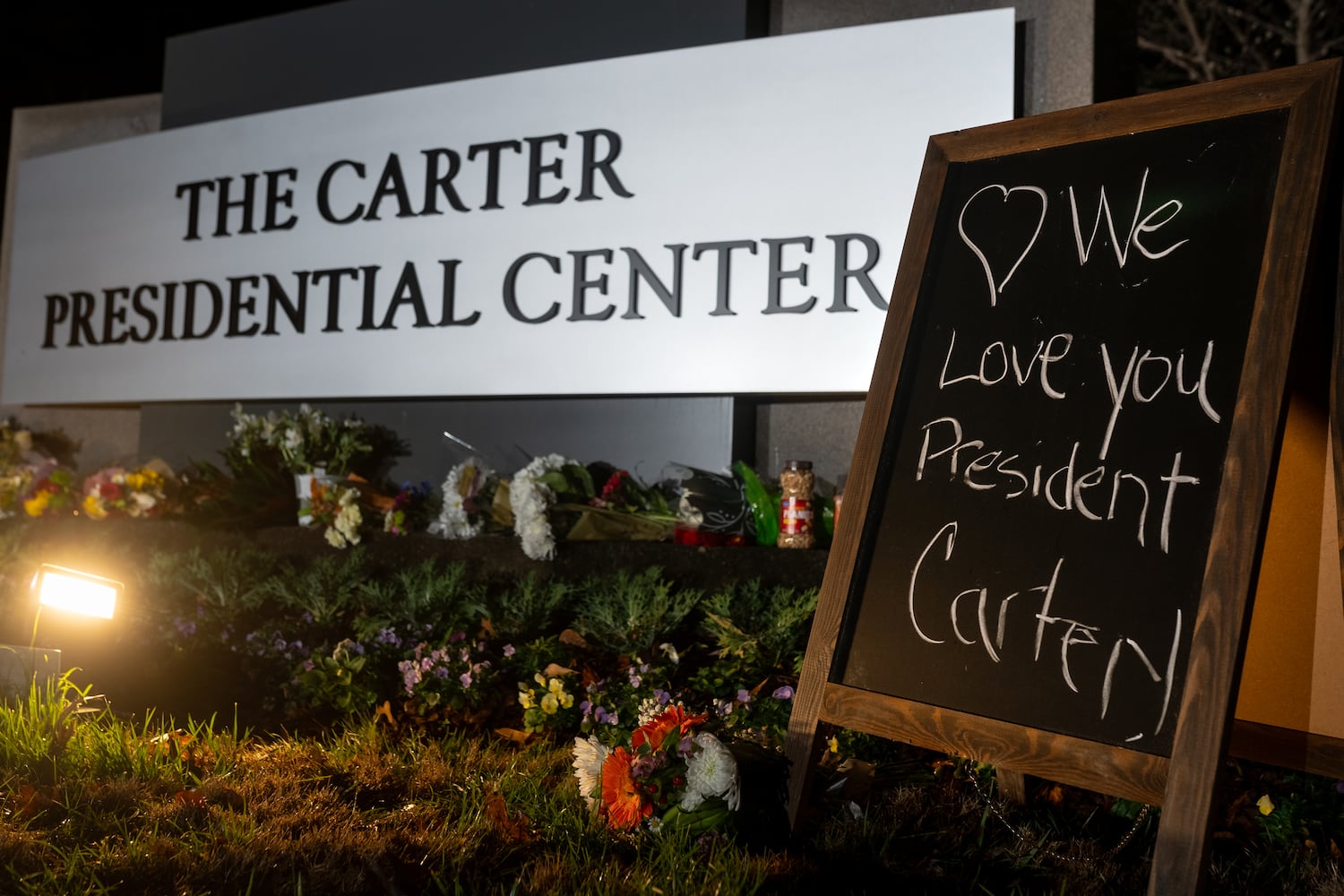 Flowers, candles and peanuts line the sign at The Carter Presidential Center in Atlanta,Georgia after the death of the former president.