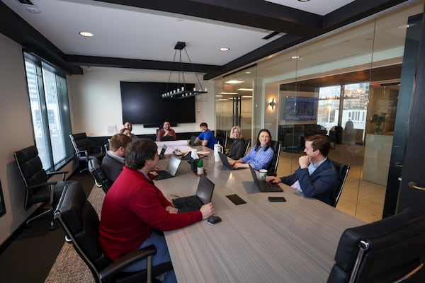 Employees with Landmark Properties conduct a meeting in the main conference room near the lobby at their Buckhead office on March 4 in Atlanta. Landmark Properties is growing its real estate presence in Atlanta. They’re handling a high-profile student housing tower near The Varsity and have experienced two office expansions in recent years. (Jason Getz/AJC)