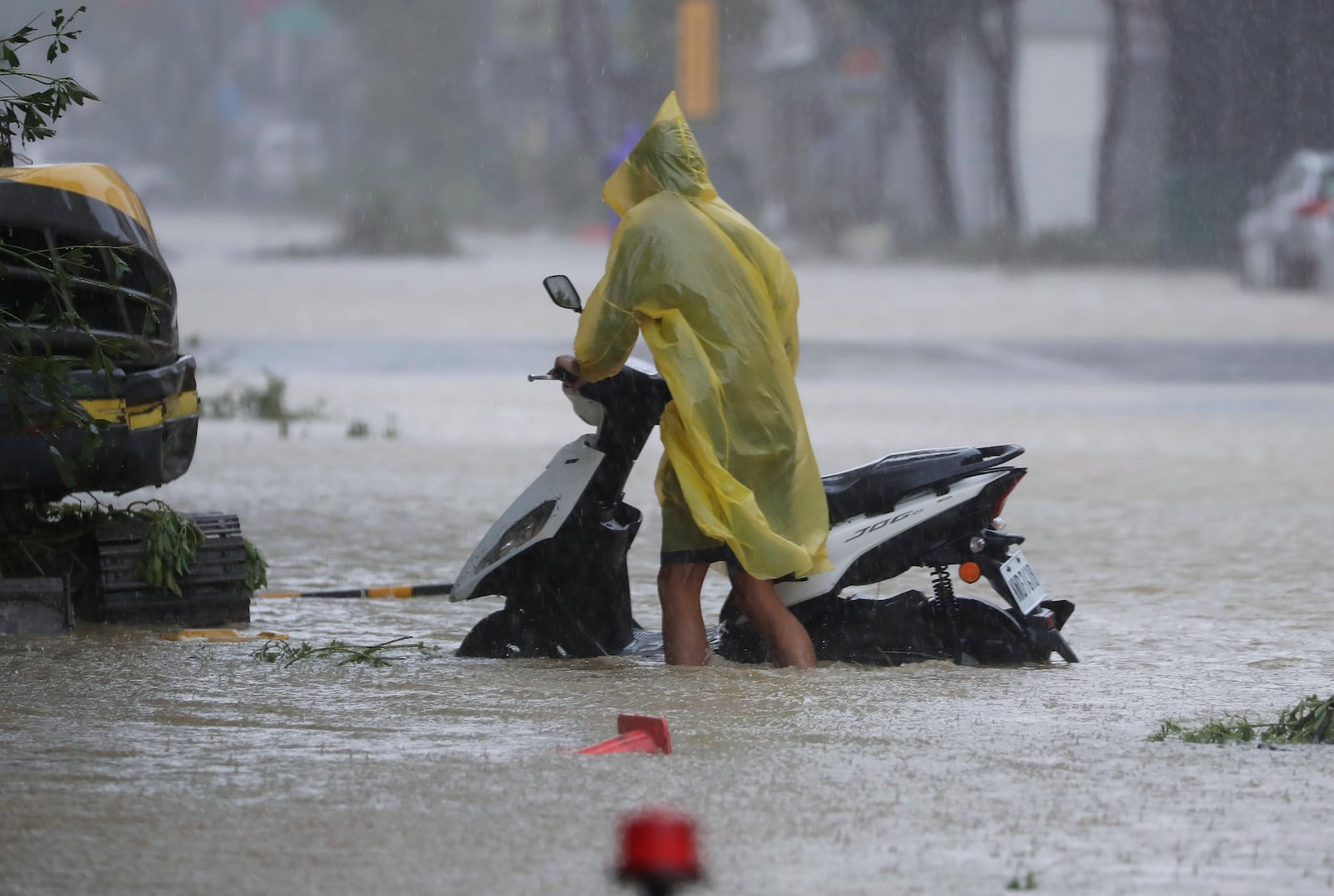 A man pushes a motorbike through a flooded road as Typhoon Krathon makes landfall in Kaohsiung, southern Taiwan, Thursday, Oct. 3, 2024. (AP Photo/Chiang Ying-ying)