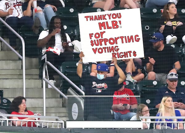 A fan -- wearing a Braves jersey and a Cubs hat -- holds a sign thanking Major League Baseball for "supporting voting rights" during a game April 26 at Truist Park following the decision to move the All-Star game out of Atlanta to protest against the state's new voting law, Senate Bill 202. (Curtis Compton / Curtis.Compton@ajc.com)