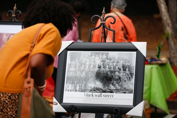 Aisha Brown looks at a photo of members of the original Black Wall Street in Tulsa, Oklahoma, at the soft opening of the New Black Wall Street in Stonecrest, Georgia, on Saturday, May 29, 2021. (Rebecca Wright for The Atlanta Journal-Constitution)