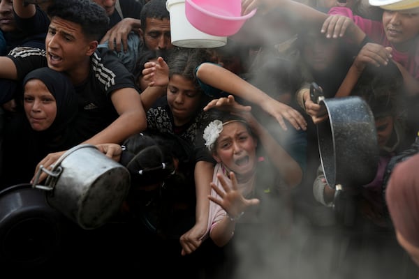 A Palestinian girl struggles as she and others try to get donated food at a distribution center in Beit Lahiya, northern Gaza Strip, Sunday, March 16, 2025. (AP Photo/Abdel Kareem Hana)