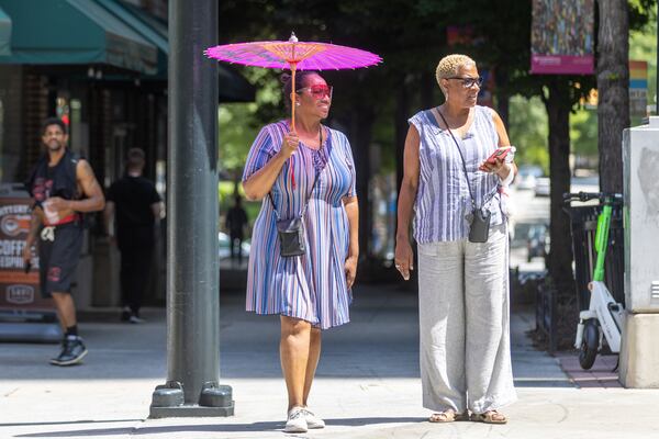 (L-R) Sabrina Zinamin and Denise Jennings walk down Peachtree Street near 10th street in Atlanta on Thursday, July 13, 2023. (Arvin Temkar / arvin.temkar@ajc.com)