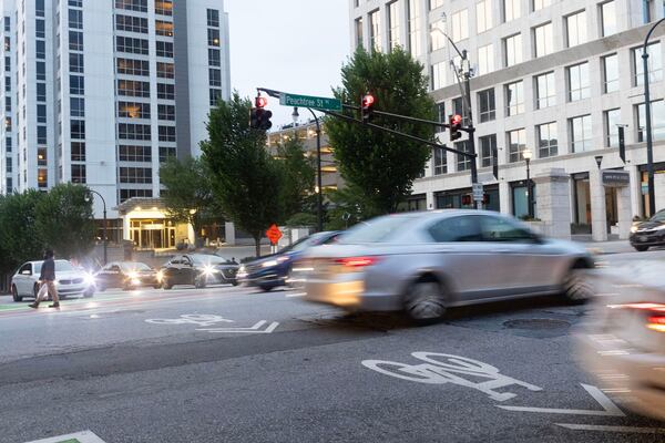 Pedestrians and cars pass travel along Peachtree Street in July. AJC