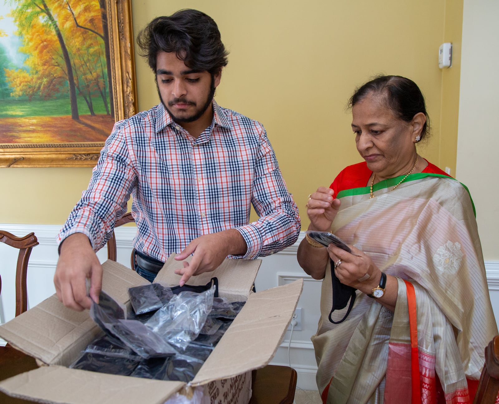 Westminster School senior Azeez Ishaqui (left) and his grandmother Najma look through a box of face masks that just arrived in their Smyrna home. During the pandemic Azeez came up with an idea to have women from India sew face masks that he would donate to homeless shelters in metro Atlanta. His Grandmother helped him accomplish that with her connections there. He was a high school freshman when he started helping the poor in India, first providing carts for men selling goods, and then later providing sewing machines for widows so they could earn a living. His parents are both from India, and he has always been encouraged to help the poor there.  PHIL SKINNER FOR THE ATLANTA JOURNAL-CONSTITUTION.