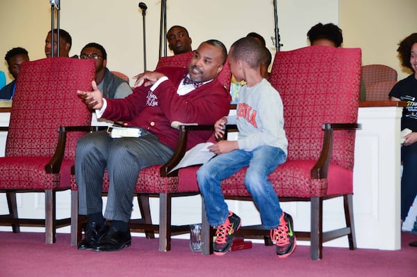 The Rev. Charles L. Fischer III confers with his son Charles IV during a college day program at Providence Missionary Baptist Church, where Fischer, pastor of St. Paul’s Episcopal Church in Atlanta, was the guest speaker. CONTRIBUTED