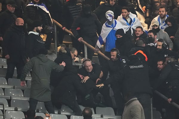 Security personnel detain a person as fans argue on stands during the UEFA Nations League soccer match between France and Israel at the Stade de France stadium in Saint-Denis, outside Paris, Thursday Nov. 14, 2024. (AP Photo/Thibault Camus)