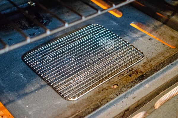 Placing a metal cooling rack on the bottom of the oven creates another “oven” rack when more space is needed. (Virginia Willis for The Atlanta Journal-Constitution)