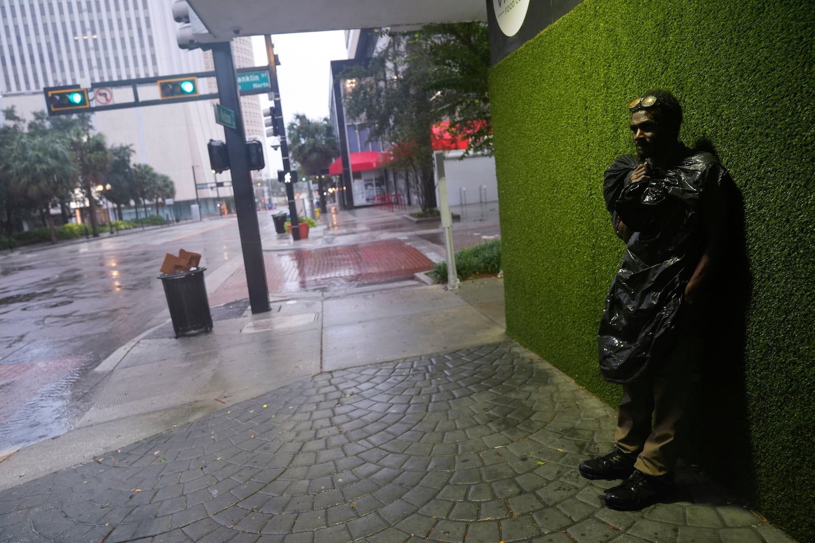 Melvin Lee HIcks, who is homeless, wears a trash bag to protect against wind-driven rain, as he stands on a street in downtown Tampa, Fla., during the approach of Hurricane Milton, Wednesday, Oct. 9, 2024. (AP Photo/Rebecca Blackwell)