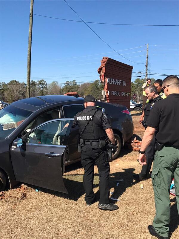 Police inspect the area where a driver crashed into a brick Department of Public Safety sign in Alpharetta.