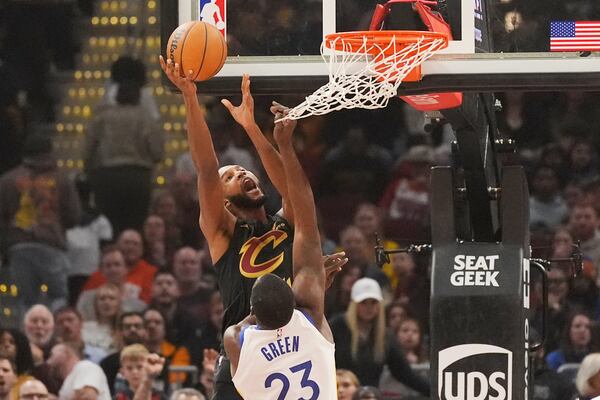 Cleveland Cavaliers forward Evan Mobley (4) shoots as Golden State Warriors forward Draymond Green (23) defends in the first half of an NBA basketball game, Friday, Nov. 8, 2024, in Cleveland. (AP Photo/Sue Ogrocki)