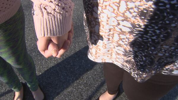 The now 21-year-old victim in a Towns County sexual assault case and her mother, Laurie Wilson, hold hands while taking a walk in their neighborhood in Blairsville earlier this year. 