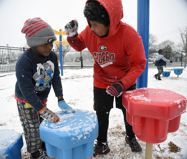 Troy Jones (left), Adorian Sammons and Zrion Jones (back) play in the snow at the Mack Gaston Community Center in Dalton on Tuesday. (Credit: Matt Hamilton / Dalton Daily Citizen-News)