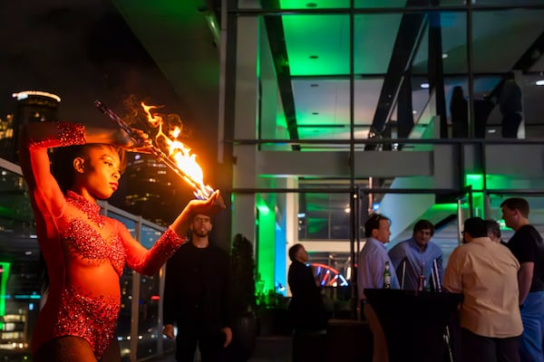 A dancer spins a flaming torch to entertain guests at Allen Porter's extravagant unveiling party for his patented, legal cannabis-infused drink at Ventanas rooftop, Atlanta, GA, on March 9, 2024. (Olivia Bowdoin for the AJC).