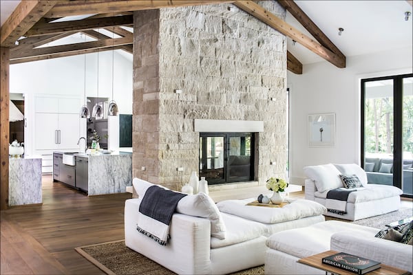 To separate from the farmhouse pack, the home includes modern, low-slung couches in the living room and contemporary lighting above the waterfall edge island in the kitchen. Photo: Courtesy of Harrison Design / Jeff Herr