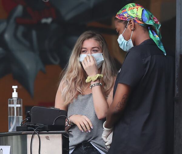 Fritti employees wear masks while waiting to seat patrons for meals at the restaurant on Tuesday, May 26, 2020, in Atlanta. The Inman Park restaurants Sotto Sotto and Fritti reopened to dine-in customers as soon as legally allowed, but employees of the restaurants have said chef/owner Ricardo Ullio has not put appropriate measures in place to protect them or the diners who have come flooding back. CURTIS COMPTON CCOMPTON@AJC.COM