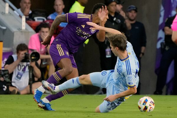 Orlando City's Wilder Cartagena, left, goes past Atlanta United's Aleksey Miranchuk during the second half of an MLS Semifinal Conference playoff soccer match, Sunday, Nov. 24, 2024, in Orlando, Fla. (AP Photo/John Raoux)