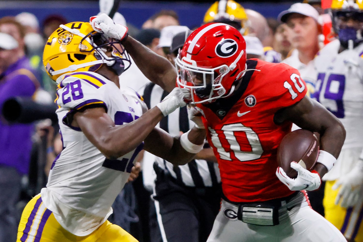 Georgia Bulldogs wide receiver Kearis Jackson (10) stiff arms LSU Tigers safety Major Burns (28) who grabs his face mask during the second half of the SEC Championship Game at Mercedes-Benz Stadium in Atlanta on Saturday, Dec. 3, 2022. (Bob Andres / Bob Andres for the Atlanta Constitution)