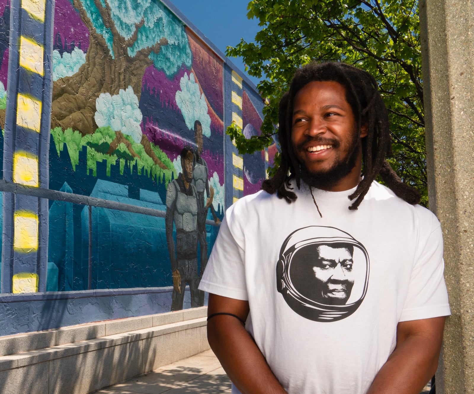 Tim Short stands in front of his mural "Earthseed" at Squash Blososm Boutique. (Brock Scott/On The Grid)