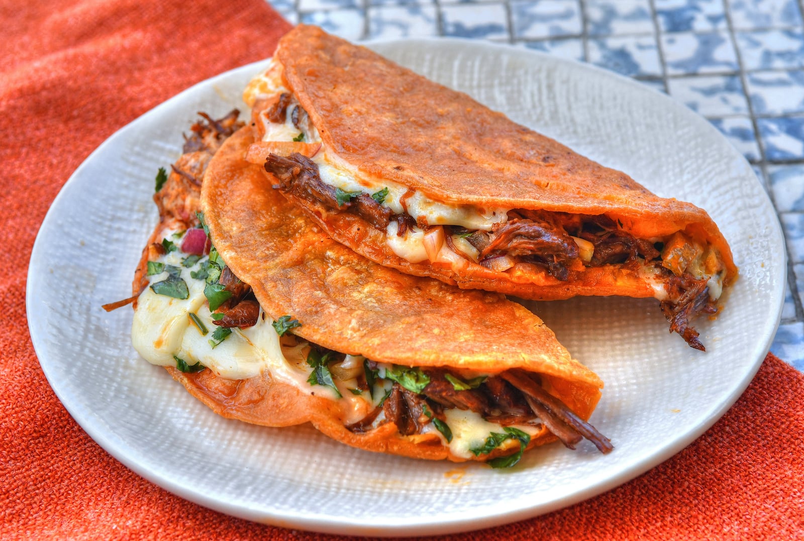 Coating the tortillas in reserved fat from the Birria de Res recipe is a key part of getting Quesabirria Tacos right. Styling by Kate Williams / Chris Hunt for the AJC