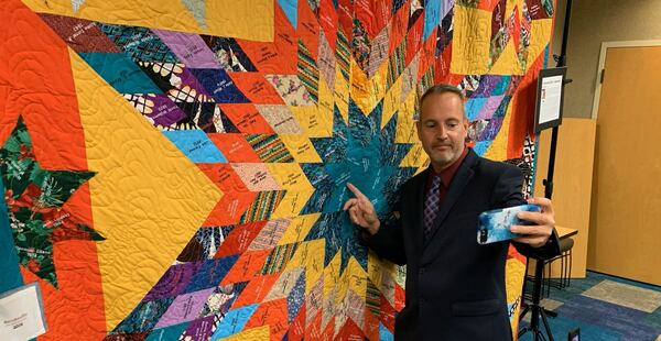 Stockbridge resident Robert Kolpak points to his family name on the city's centennial quilt. The quilt was four years in the making because the pandemic shutdown work on the project for more than two years.