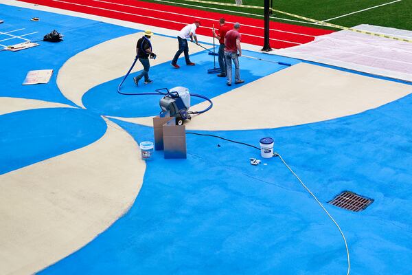 Workers with Streetbond apply a reflective paint to the basketball court at the SAE School in Mableton to reduce heat on Thursday, August 25, 2022. (Natrice Miller/ natrice.miller@ajc.com)