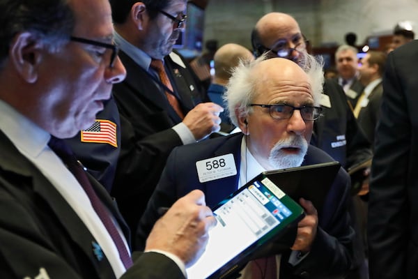 Peter Tuchman, right, works among fellow traders at a post on the floor of the New York Stock Exchange.