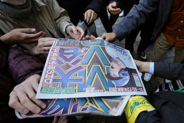 A staff member distributes an extra edition of the Sports Hochi newspaper reporting that Los Angeles Dodgers' Shohei Ohtani won his third Most Valuable Player award, Friday, Nov. 22, 2024, in Tokyo. (AP Photo/Eugene Hoshiko)