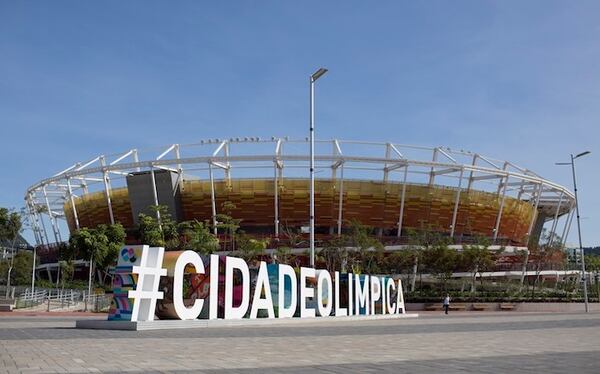 In this July 16, 2017 photo, a sign in Block letters spelling "#OLYMPIC CITY" in Portuguese, stands in front of the tennis arena at the Olympic Park, in Rio de Janeiro, Brazil. Save for minor cosmetic changes, a city fractured by mountains and searing inequality remains as it was. The games took place mostly in the south and west of the city, which remains white and wealthy. The rest is still a hodgepodge of dilapidated factories and hillside slums of cinderblocks, tin roofs and open troughs of raw sewage. (AP Photo/Renata Brito)