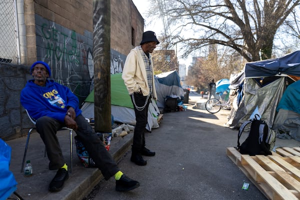 Residents, including Robert Williams (center), are seen at an encampment on Old Wheat Street in Atlanta on Tuesday, March 11, 2025. Daniel Barnett was arrested on Tuesday for allegedly slashing tents at the encampment, which is also where Cornelius Taylor was killed during a clearing in January. (Arvin Temkar / AJC)