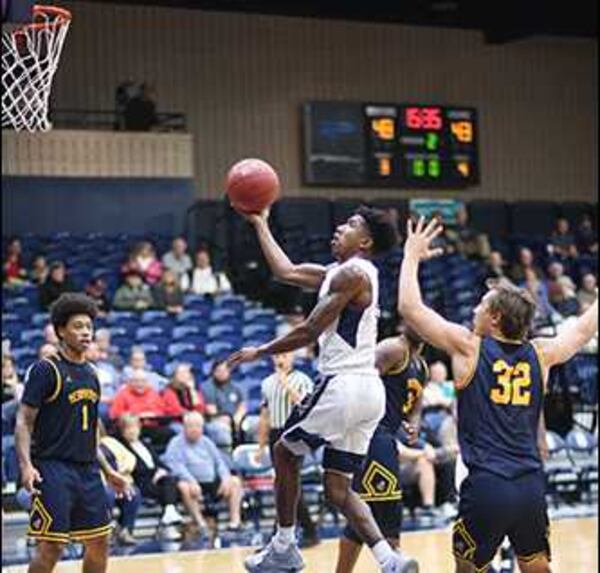 Dalton State College basketball player Kingston Frazier, in the white uniform going up for a layup, was recently honored for starting a youth basketball league to reduce violence in his hometown of Opelika, Ala. PHOTO CONTRIBUTED.